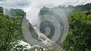 A stormy river flows along the bottom of a narrow gorge with steep slopes.