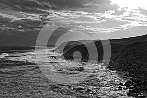 Stormy sea at rocky coast black-and-white