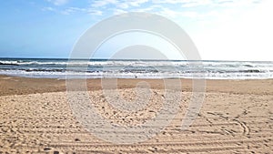 Stormy sea. The waves of stormy sea roll on sandy shore on sunny day. Weather, sea breeze. Sea waves with white foam on sand beach