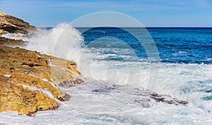 Stormy seascape with strong foamy waves of ocean water splashing against rocky shore