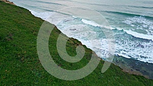 Stormy seaside green hills environment drone view. Sea waves washing sandy coast