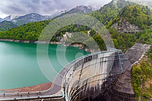 Stormy skies and snowcapped mountains next to a huge hydroelectric dam (Kurobe Dam, Japan