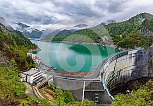 Stormy skies and snowcapped mountains next to a huge hydroelectric dam (Kurobe Dam, Japan