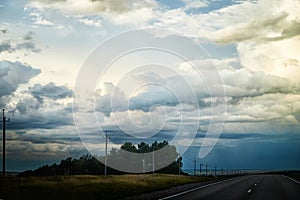 Stormy sky with gloomy dark clouds over the field. Dramatic landscape. The concept of traveling in any weather