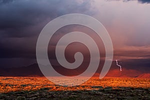 Stormy sky with lightning and dramatic sunset light in the desert