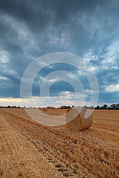 Stormy sky over field with hay bale in the foreground