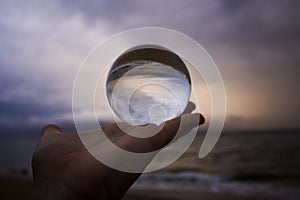 Stormy Sky and Sea at Sunset Captured in Glass Ball Held in Palm