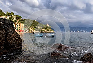 Stormy sky and small boats in sea bay of Portofino town. Portofino is small fishing town in Liguria district, Italy.