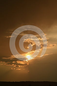 Stormy sunset. Yellow-blue clouds and the setting sun