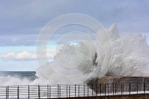 Stormy wave over old lighthouse and pier of Viavelez.