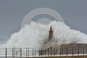 Stormy wave over old lighthouse and pier of Viavelez.