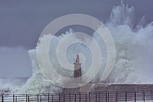 Stormy wave over old lighthouse and pier of Viavelez.