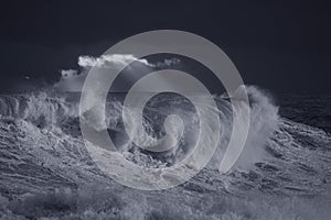 Stormy waves against dark sky at sunset