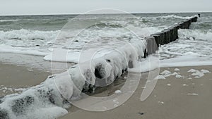 Stormy weather on Baltic sea beach. waves at the groynes and bubbles.