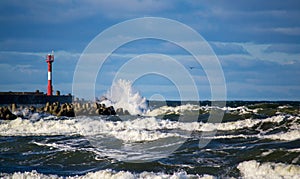 Stormy weather on the sea, wind, waves and lighthouse at a mole