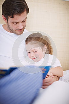 Story with a happy ending. A devoted father reading his young daughter a bedtime story.