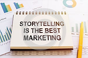STORYTELLING IS THE BEST MARKETING - written on notepad on financial charts and graphs with yellow pen