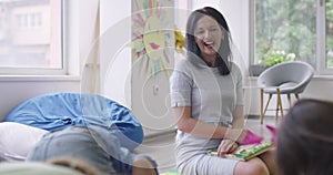 Storytime elementary or primary school teacher reading a story to a group of children in a daycare center.