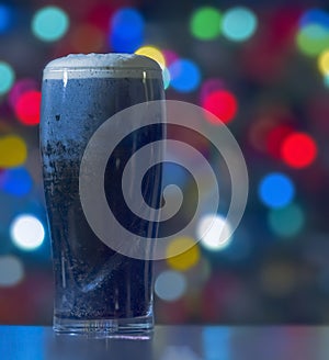 A Stouts with christmas lights on the background. Guinness dark Irish dry stout beer glass from a brewery in dublin.