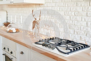 Stove in christmas kitchen. Gas-stove white kitchen furniture with christmas decor. Stylish trendy white ceramic brick wall,