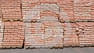 Stowed on top of each other are two rows of wooden pallets, standing with stacks of red bricks stacked on them in several levels photo
