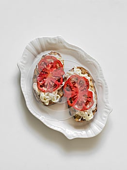 Stracciatella cheese, bruschetta tomatoes on a light background, top view