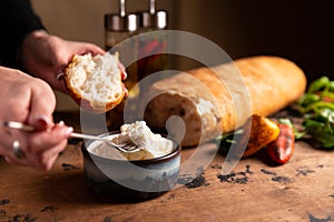 Stracciella cheese in a plate. The hand puts on the bread