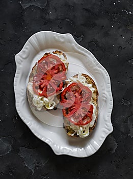 Strachatella cheese, bruschetta tomatoes on a dark background, top view