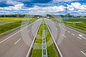 Straight asphalt highway passing through the rural area in the mountains at sun and clouds spring weather. Concept of travel