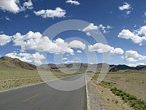 A straight asphalt road leads to the foot of the mountain in the distance