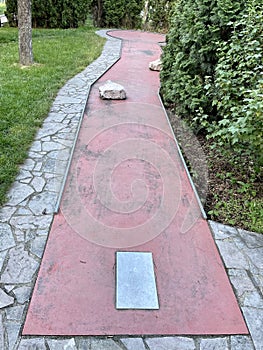 Straight clay miniature golf course with stone barriers in the middle of a green park in Prague, Czech Republic.