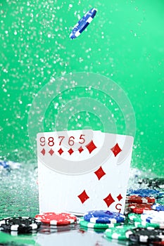 Straight combination under the water drops and falling poker chips against green background. Online gambling. Betting.