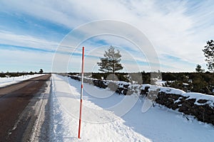 Straight country road with a snow stake by roadside