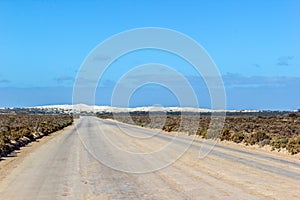 straight gravel road through the nullarbor dessert of Australia with sand hills in the distance, South Australia, Australia