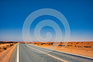 Straight highway through a desolate landscape in the Western Australian outback