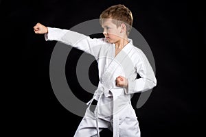 Straight karate arm hit. Kid in brand new kimono on black background