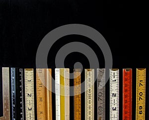 A straight line of rulers and scales in metric and inches suggest measurement, metrics, precision, accuracy