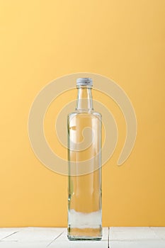 Straight long glass bottle on a light white-yellow background