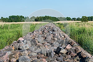 Straight old and long mole paved with stones going through the reed field till Baltic sea, Ainazi, Latvia