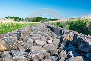 Straight old and long mole paved with stones going through the reed field till Baltic sea, Ainazi, Latvia