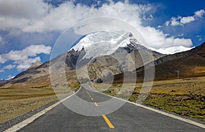 Straight road leads towards the foothills of a majestic Himalayan glacier.