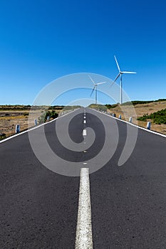 A straight road with two wind turbines