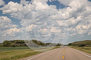 Straight Saskatchewan highway under thick, summer cloud coverage