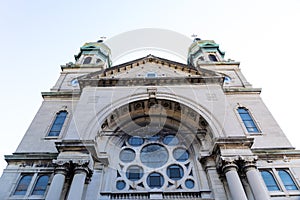 Straight on view of a gray stone church with verdigris copper cupolas, rose window photo