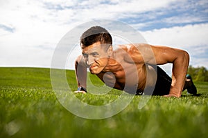 Strained man is doing press-ups on lawn