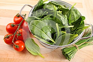 Strainer with spinach leaves and tomatoes photo