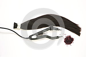 a strand of hair for extension with a device for encapsulation and keratin in granules on a white background