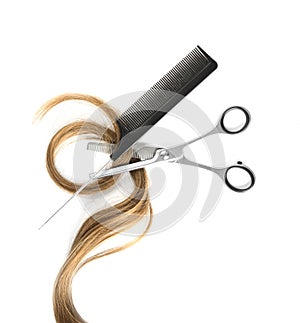 Strand of light brown hair, comb and thinning scissors on white background, top view.