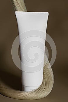 A strand of natural dark hair for extensions with a bottle of care product.