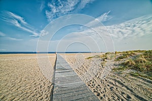 Romantic wooden trail or boardwalk on a beach leads to a calm Baltic Sea conveying realisation concept. Success path illustration